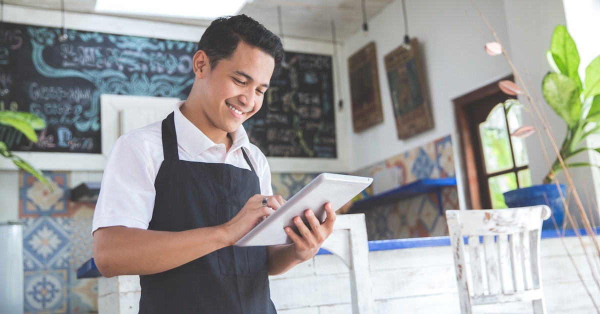 An image of a man holding a tablet while working inside his small business.