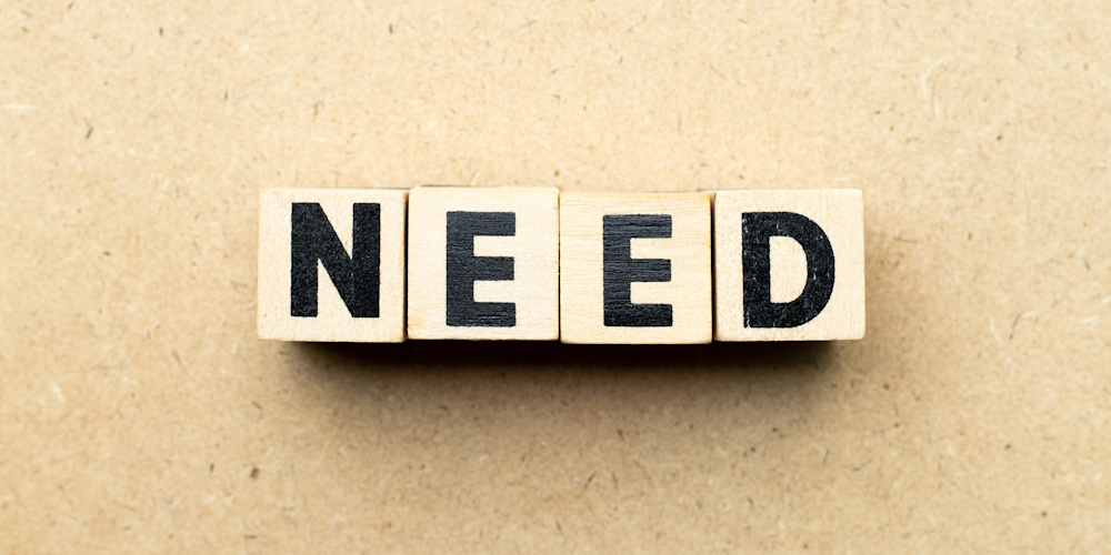 An image of four wooden blocks that spell the word "NEED."