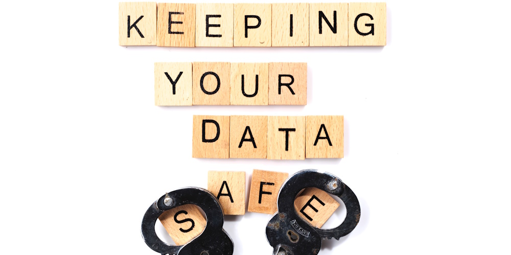 An image of wooden blocks spelling out "keeping you data safe" with handcuffs sitting on top of the s and e in safe.