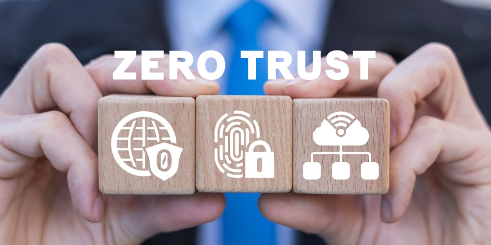 An image of a person holding wooden blocks with images that represent zero trust security, and the word "ZERO TRUST" above them.