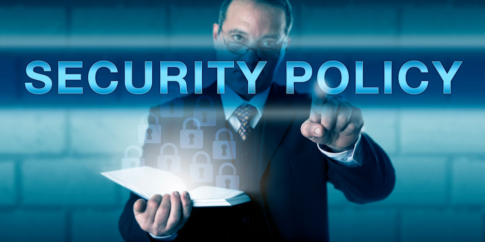 An image of a man holding a book and pointing to text in front of him that reads "security policy."