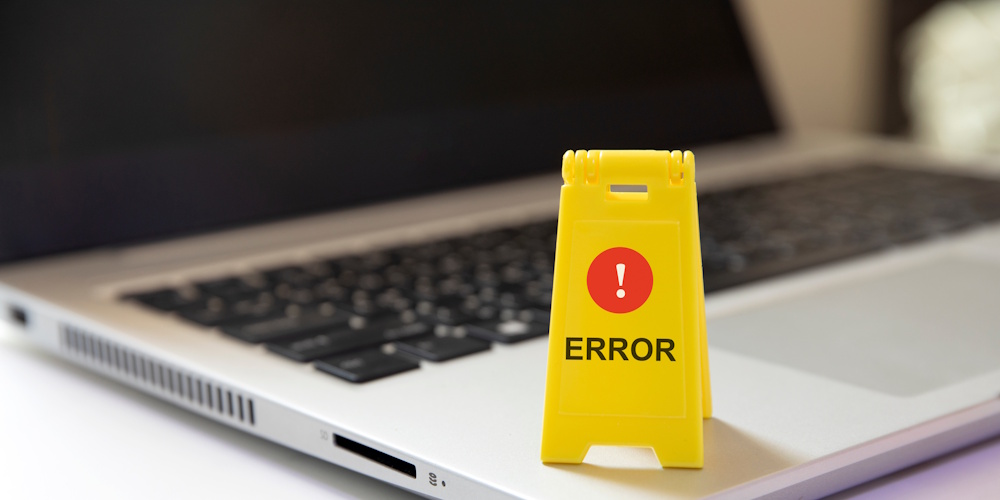 An image of a laptop with a small yellow warning sign sitting on it that reads error.