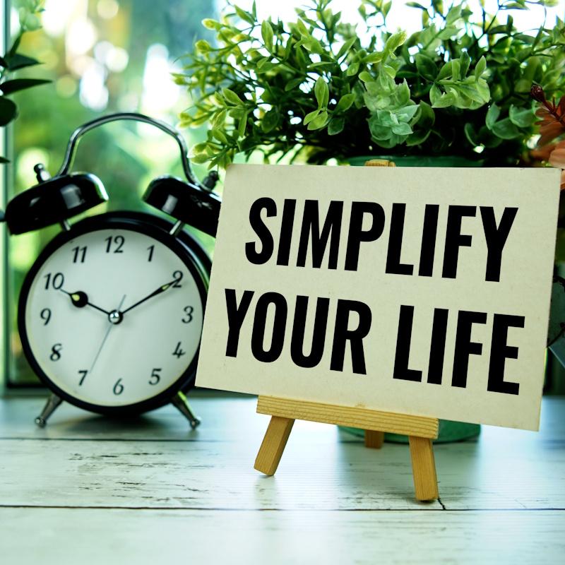 An image of a table with flower pots, a clock, and a sign that reads "simplify your life."
